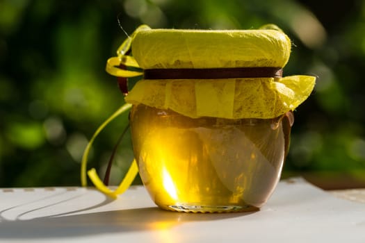 Jar with honey on table against nature background