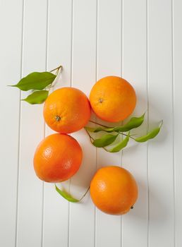 Four whole ripe oranges and leaves
