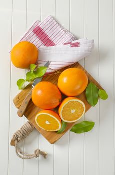 Whole ripe oranges and two halves on cutting board