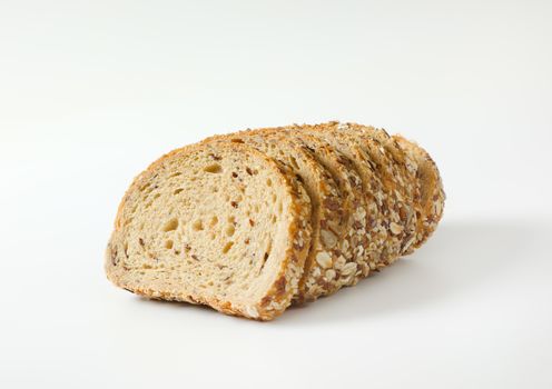 Sliced loaf of whole grain bread, crust topped with rolled oats and seeds (flax, sesame, sunflower)