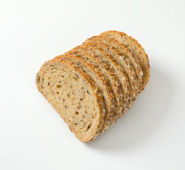 Sliced loaf of whole grain bread, crust topped with rolled oats and seeds (flax, sesame, sunflower)