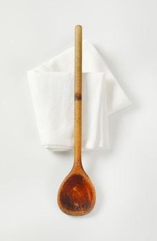 Old wooden cooking (stirring) spoon on white napkin