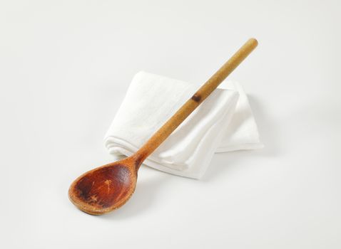 Old wooden cooking (stirring) spoon on white napkin