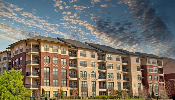 A modern brick apartment complex against a blue sky with clouds