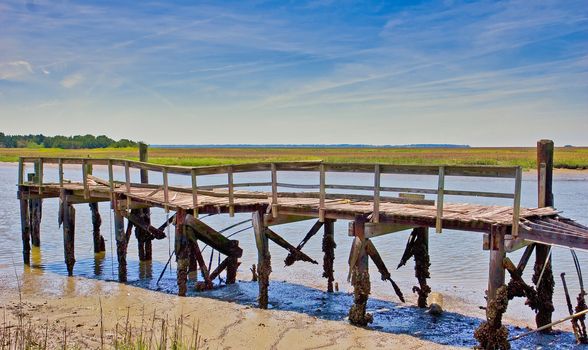 An old pier falling apart on the edge of the marsh and the mud