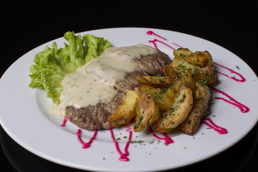 Beautiful and healthy food on a white plate. Fried meat, poured with sauce, French fries with dill, green salad. Fried meat and French fries