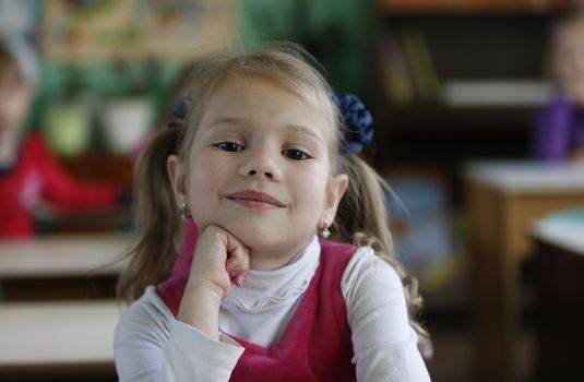 Little girl, the child is sitting in the kindergarten at the table, smiling.Pre-school girl