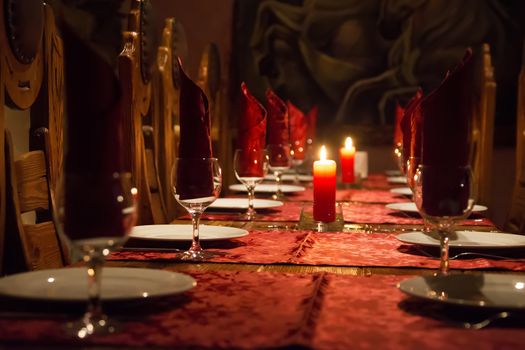 The restaurant has a rich wooden table, claret tablecloths, wooden expensive chairs, candles on the table, glasses.Cheap cafe. Dinner table. Empty restaurant.