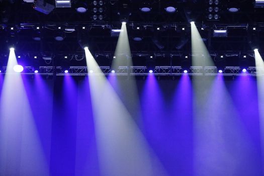 Concert spotlights.Blue and white rays of powerful projectors on stage