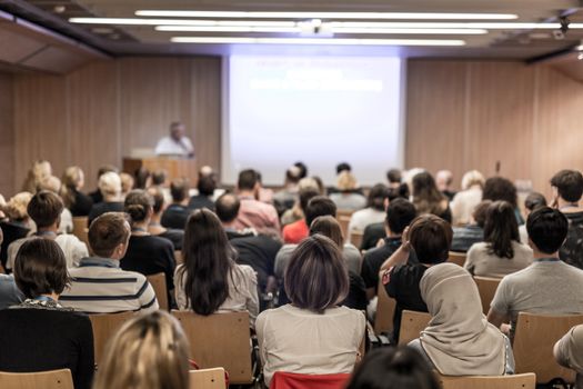 Speaker giving a talk in conference hall at business event. Audience at the conference hall. Business and Entrepreneurship concept. Focus on unrecognizable people in audience.