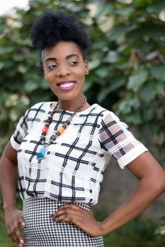 Pretty smiling woman posing in outdoors with foliage in background