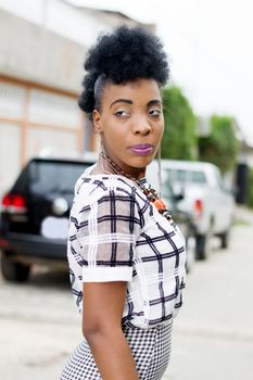 Pretty African American woman looking behind in an alley of her neighborhood