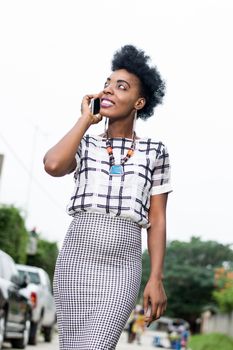 Beautiful African woman phoning in the street with a beautiful smile.