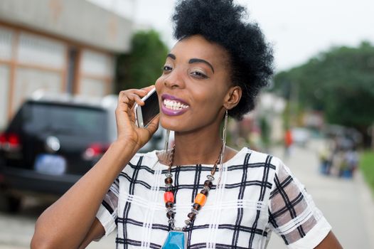 Portrait of pretty African woman in communication in the street with a beautiful smile