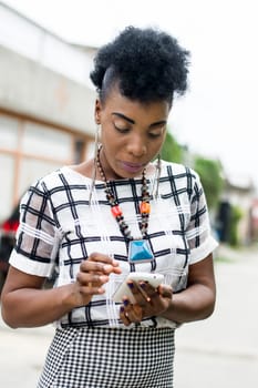 Portrait of African woman focused on her mobile phone.