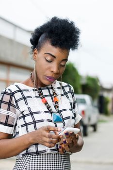 Portrait of African woman focused on her mobile phone.