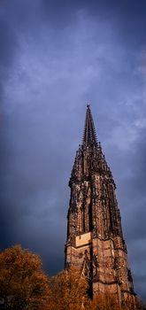 The burned spire of St. Nicholas church (St.-Nikolai-Kirche), a Gothic Revival cathedral who was one of the five Lutheran churches in Hamburg, Germany. Black church spire and stormy sky.