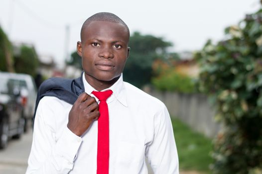 Portrait of young African businessman with his jacket on his shoulder.
