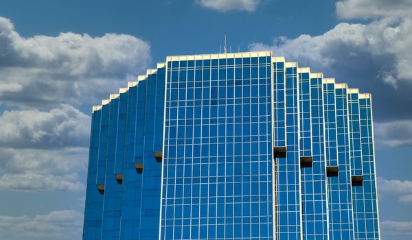 A blue glass office tower against a blue sky
