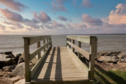 An old weathered walkway across a seawall toward the beach