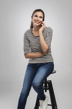 Beautiful happy young woman sitting on a bench making a phone call
