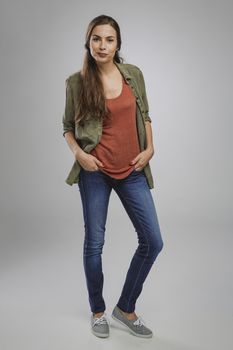 Beautiful young woman smiling and standing over a gray background