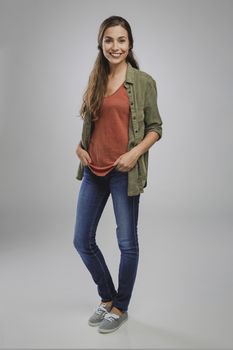 Beautiful young woman smiling and standing over a gray background