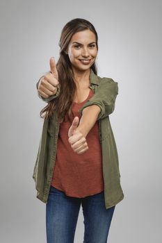 Beautiful woman over a gray background with thumbs up