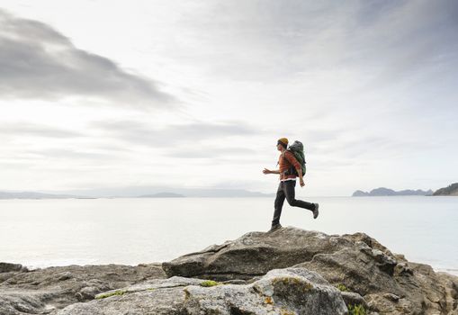 Man with backpack running over the rocks 