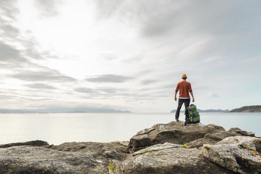 Man with backpack enjoying  the beautiful morning view of the coast