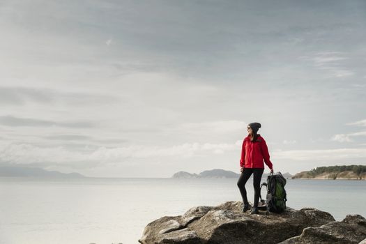 Woman with backoack enjoying the morning view of the coast