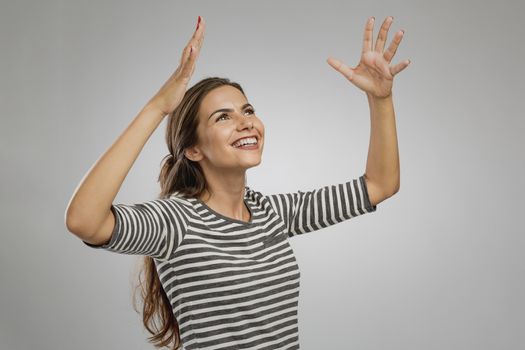 Portrait of a beautiful happy woman with arms raised and looking up