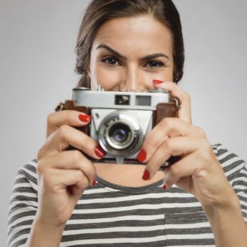 Beautiful woman holding her vintage camera over the face