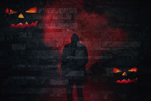 Halloween silhouette of a scary person in red smoke with evil pumpkin faces on a brick wall background