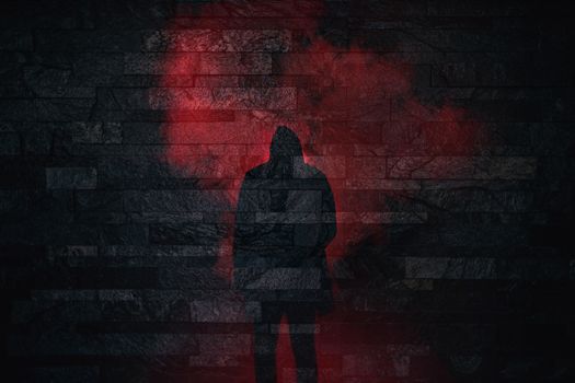 Halloween scary silhouette of a person standing in red smoke on a brick wall background