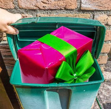 pink christmas present with green ribbon in a classical green mailbox