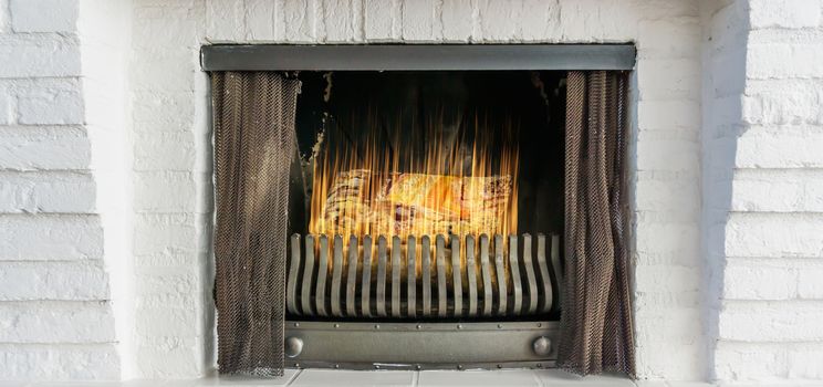 Burning fireplace with iron curtains in closeup winter background