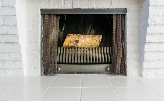 Unlit Fire place with white architecture and non burning logs inside background