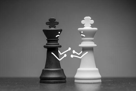 Two black and white king chess pieces with hand drawn faces and arms having a fist fight over a grey background viewed low angle