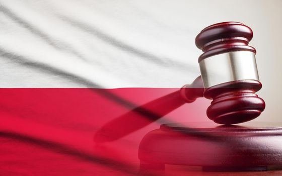 Legal gavel on its plinth over a flag of the Poland in a conceptual composite image