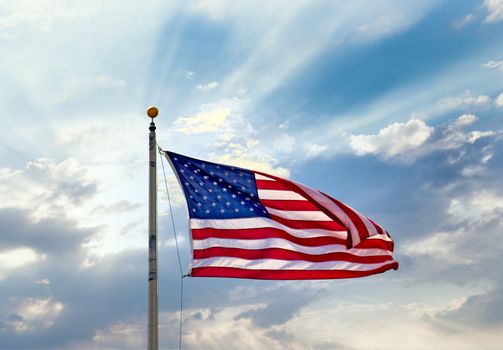 An American flag on a flagpole against blue sky and clouds