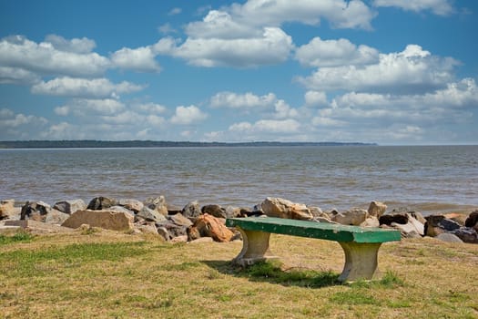 An old weathered green concrete bench by the edge of the sea