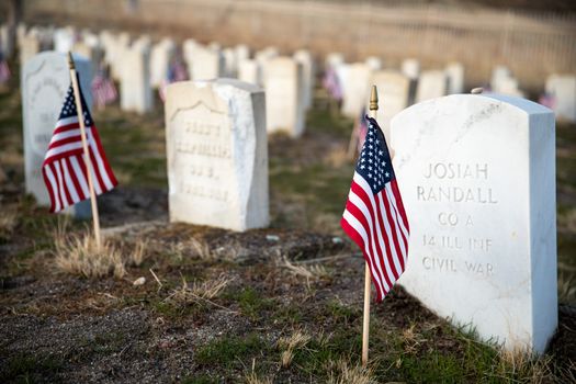 flags in front of the headstones of fallen soldiers