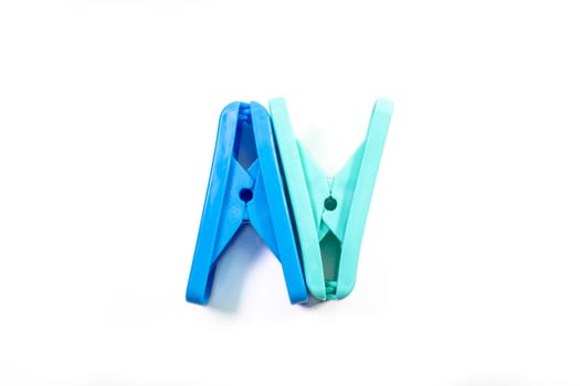 The close up of light green clothes peg and blue clothes peg on white background.