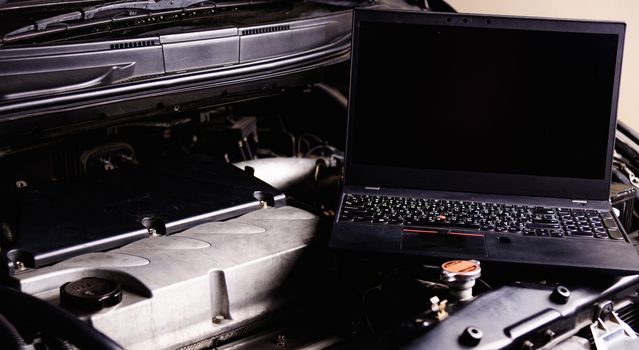 Laptop computer on car mechanic engine for service at workshop