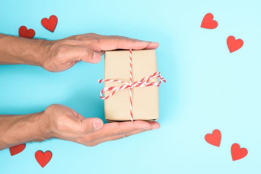 Valentine's Day Concept, Top view Flat lay, have red heart and hand holding gift box on blue background with copy space for your text