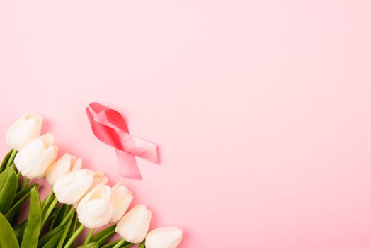 Breast cancer month concept, flat lay top view, pink ribbon and Tulip Flower on pink background with copy space for your text