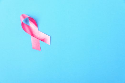 Breast cancer month concept, flat lay top view, pink ribbon on blue background with copy space for your text