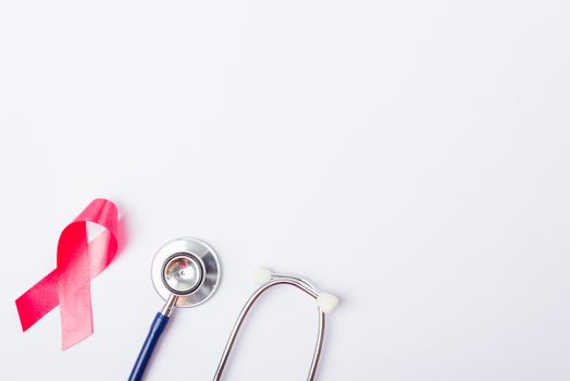 Breast cancer month concept, flat lay top view, pink ribbon and stethoscope on white background with copy space for your text