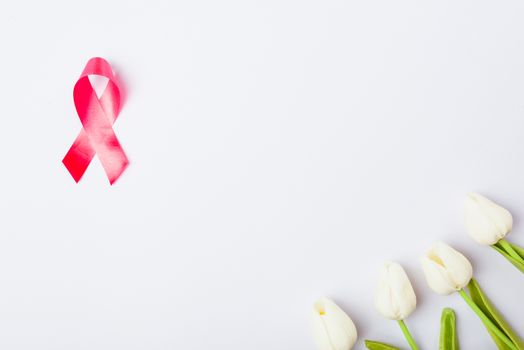 Breast cancer month concept, flat lay top view, pink ribbon and Tulip Flower on white background with copy space for your text